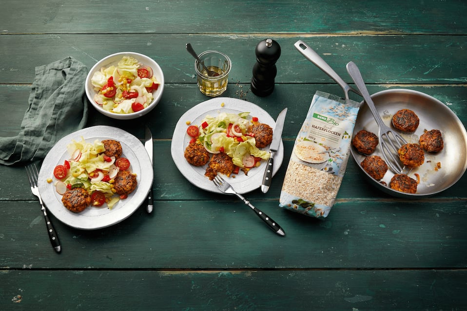 Haferflocken-Bratlinge mit Zucchini und Möhren auf buntem Salat